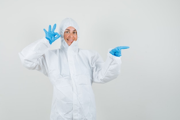 Kobieta lekarz w kombinezonie ochronnym, rękawiczki skierowane w bok