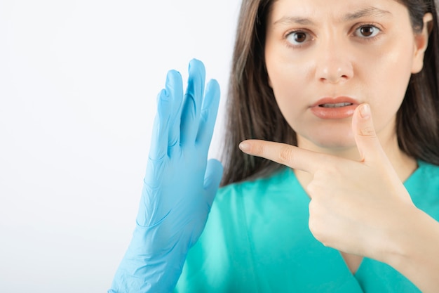 Kobieta lekarz w rękawiczkach medycznych pokazując ręce na białym.