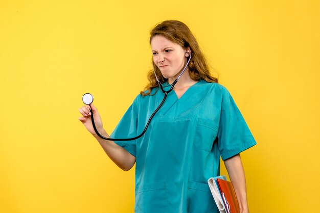 Kobieta lekarz widok z przodu z plikami i stetoskopem na żółtej przestrzeni