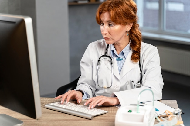 Kobieta lekarz wpisując na komputerze przy biurku