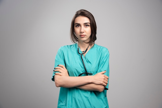 Kobieta lekarz ze stetoskopem, stojąc na szarym tle. Wysokiej jakości zdjęcie
