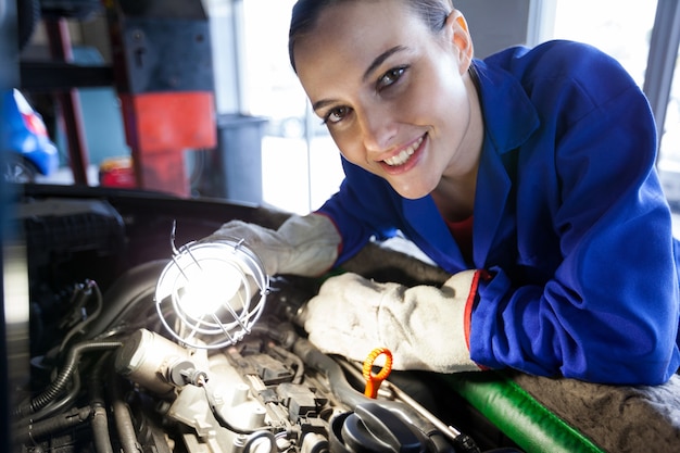 Bezpłatne zdjęcie kobieta mechanika samochodowego silnika badając