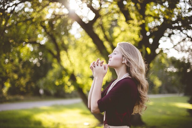 Kobieta modli się pod drzewem w ciągu dnia