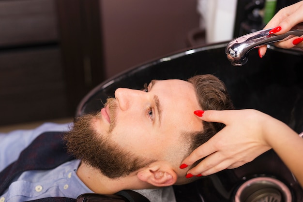 Kobieta myje włosy klienta przy fryzjera męskiego sklepu zakończeniem