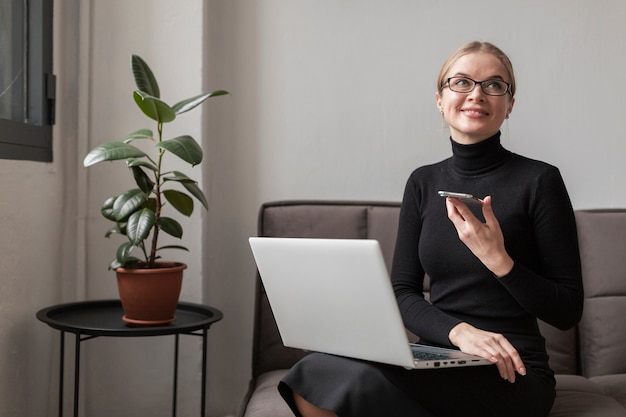 Kobieta na kanapie z telefonem komórkowym i laptopem