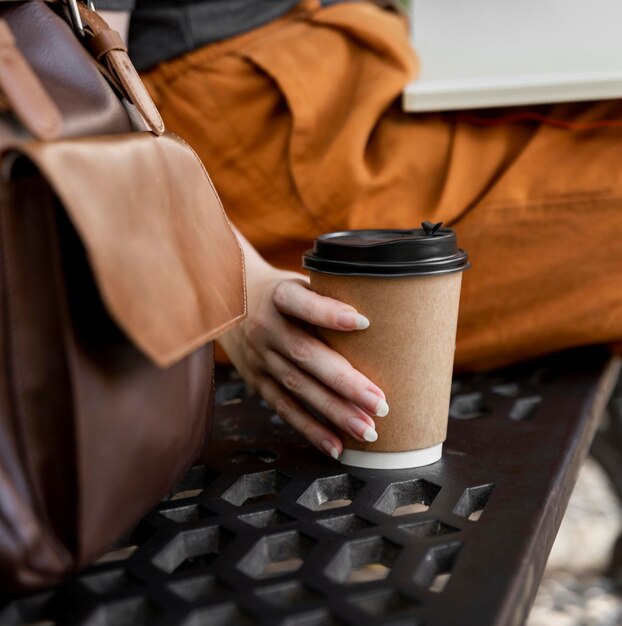 Kobieta na ławce chwytając kawę