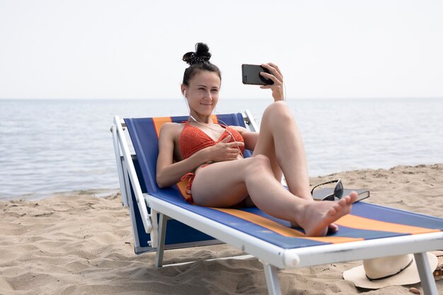 Kobieta na plażowym krześle bierze selfie