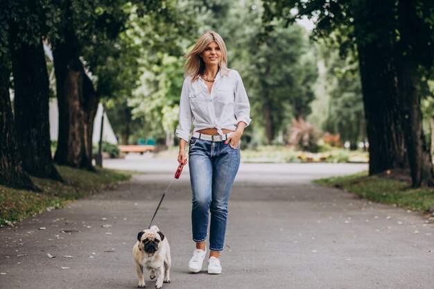 Kobieta na spacerze w parku ze swoim zwierzakiem-mopsem