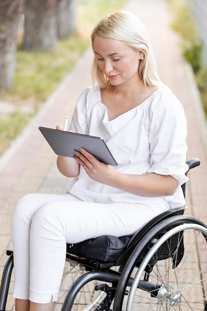 Kobieta na wózku inwalidzkim z tabletem na zewnątrz