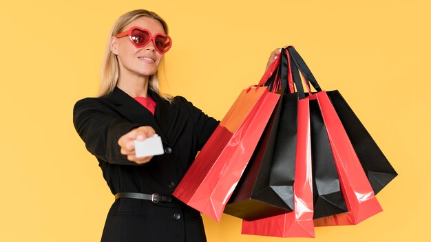 Kobieta na zakupy w czarny piątek pokazując torby i kupon