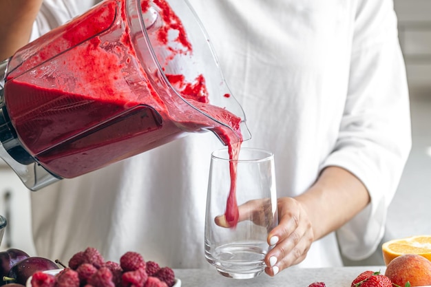 Bezpłatne zdjęcie kobieta nalewa koktajl jagodowy z blendera do szklanki