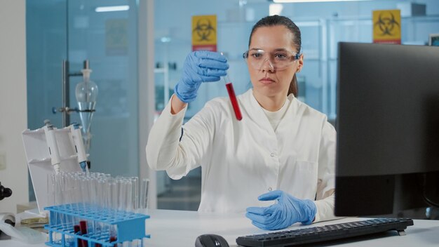 Kobieta naukowiec patrząca na substancję dna w probówce, używająca szkła laboratoryjnego do badania płynu do eksperymentu naukowego. lekarz pracujący z próbką w szklanej kolbie w celu opracowania analizy.