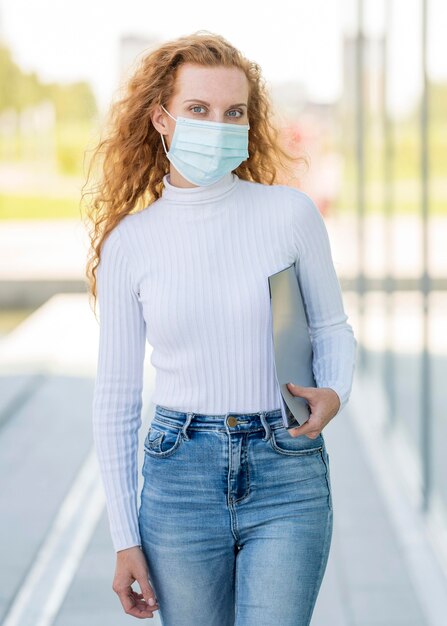 Bezpłatne zdjęcie kobieta nosi maskę medyczną na zewnątrz