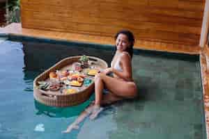 Bezpłatne zdjęcie kobieta o tropikalne zdrowe śniadanie w willi na pływającym stole