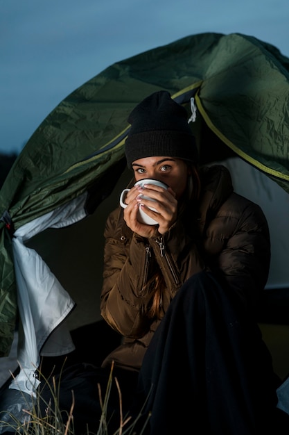 Kobieta obozująca w nocy przy filiżance herbaty