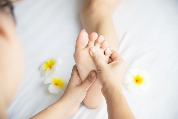 Kobieta odbiera usługi masażu stóp z masażystka bliska pod ręką i stóp - zrelaksować się w koncepcji usługi terapii masażu stóp