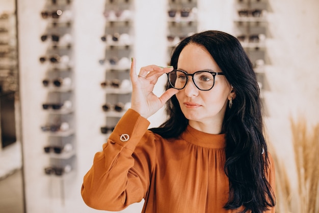 Kobieta okulista demonstruje okulary w sklepie optycznym