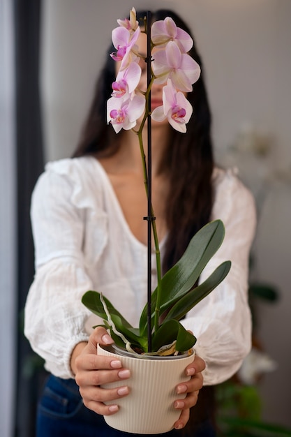 Bezpłatne zdjęcie kobieta ozdabiająca dom kwiatami orchidei