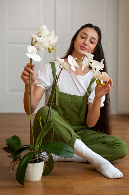 Bezpłatne zdjęcie kobieta ozdabiająca dom kwiatami orchidei