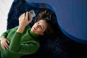 Bezpłatne zdjęcie kobieta patrząca na swojego smartfona leżąc na podłodze