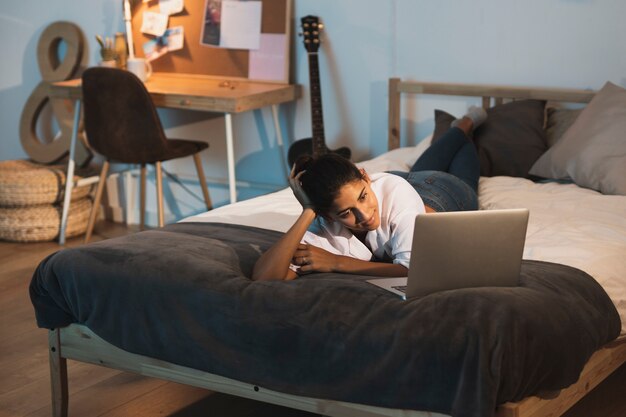 Kobieta patrzeje na laptopie i relaksuje w łóżku