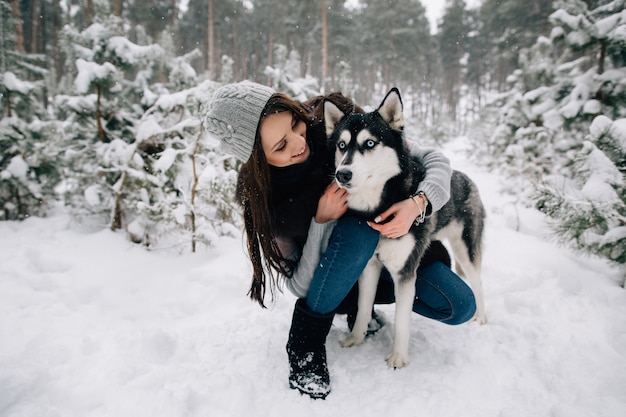 Bezpłatne zdjęcie kobieta pieści psa husky w zimie śnieżny zimny dzień