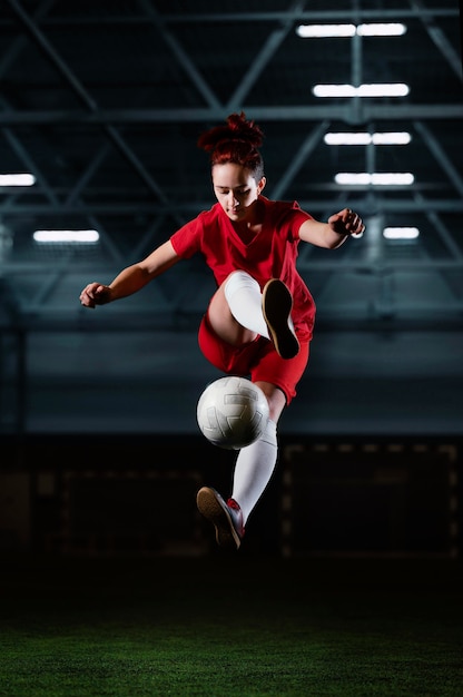 Bezpłatne zdjęcie kobieta piłkarz kopiąc piłkę