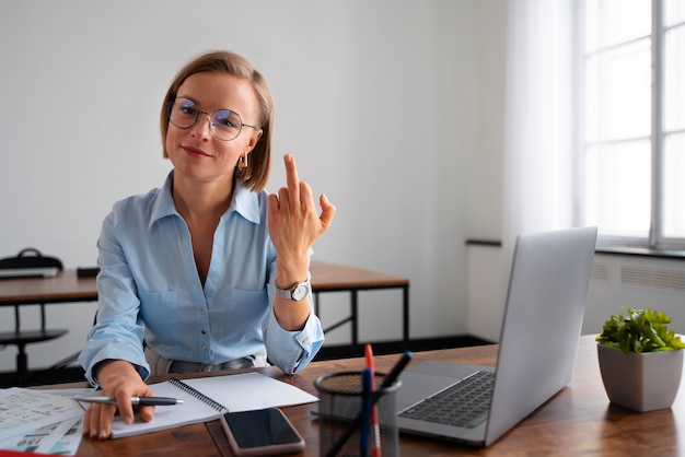 Bezpłatne zdjęcie kobieta pokazuje gest środkowego palca podczas pracy w biurze