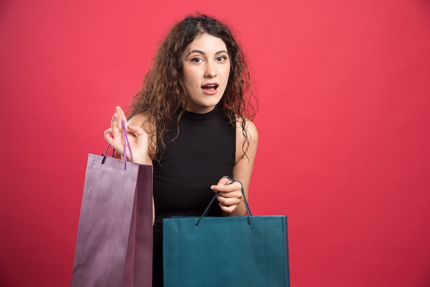 Kobieta Pokazuje Jej Zakupy Na Czerwonym Tle. Wysokiej Jakości Zdjęcie