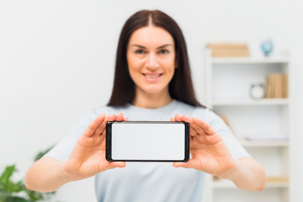 Kobieta pokazuje smartphone z pustym bielu ekranem