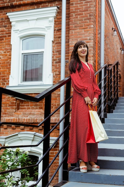 Kobieta pozuje na zewnątrz na schodach z torby na zakupy
