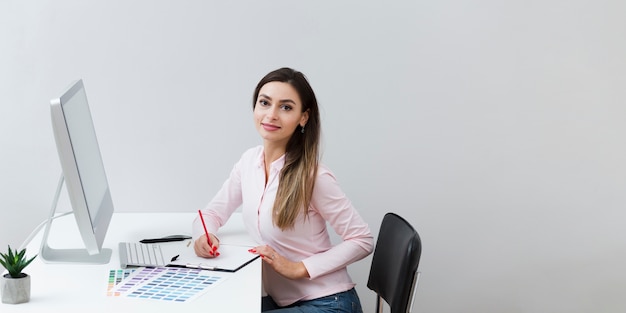 Bezpłatne zdjęcie kobieta pozuje podczas gdy pracujący przy komputerem