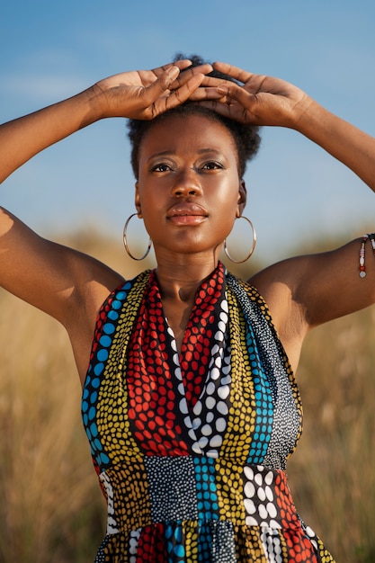 Kobieta pozuje w suchym środowisku, nosząc rodzimą afrykańską odzież