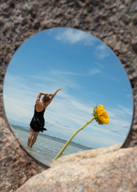 Kobieta pozuje z okrągłym lustrem i kwiatem