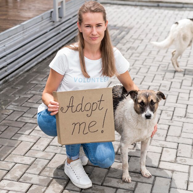Kobieta pozuje z psem i trzyma znak adoptuj mnie dla zwierzaka