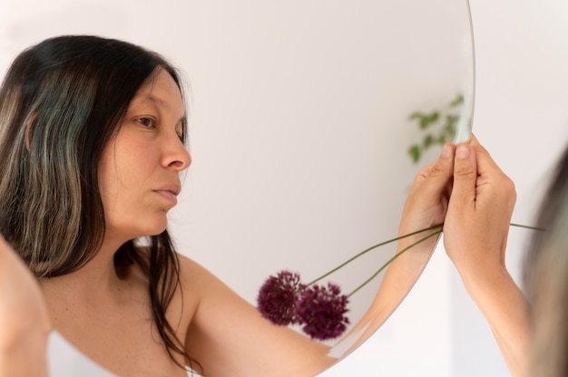 Bezpłatne zdjęcie kobieta pozuje zmysłowo z kwiatem