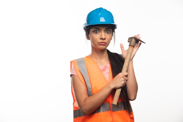 Kobieta pracownik budowlany ubrany w kamizelkę i kask trzymając młotek