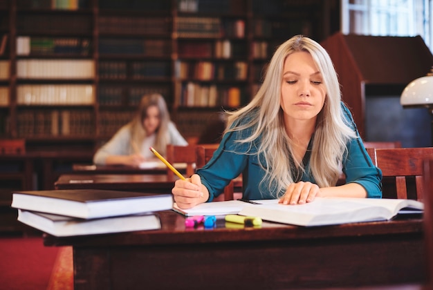 Bezpłatne zdjęcie kobieta pracująca przy biurku robiąca notatki