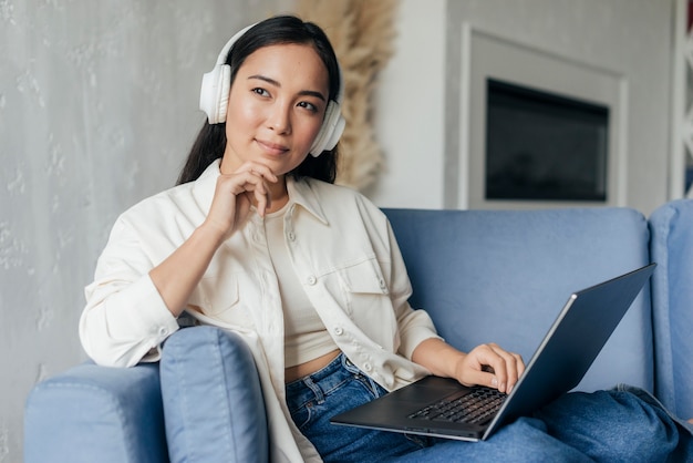 Kobieta pracuje na laptopie ze słuchawkami