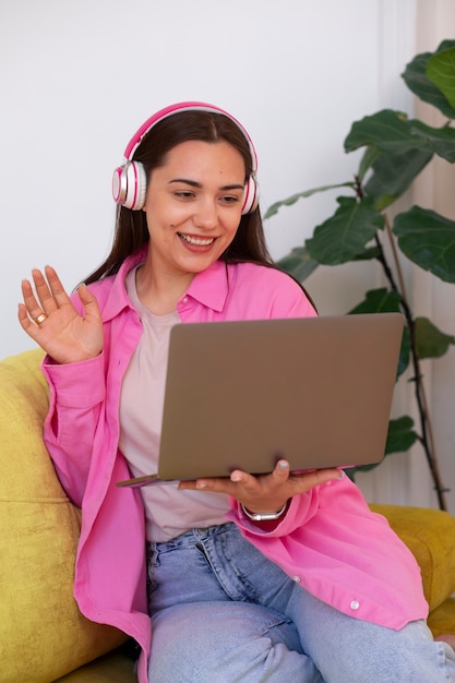 Bezpłatne zdjęcie kobieta prowadząca rozmowę wideo na laptopie, siedząc na kanapie w domu