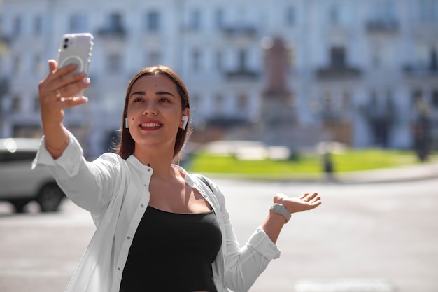 Bezpłatne zdjęcie kobieta prowadząca rozmowę wideo na smartfonie, będąc na zewnątrz w mieście