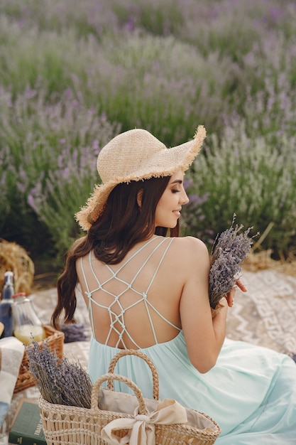Kobieta Prowansji relaks w lawendowym polu. Pani w niebieskiej sukience i słomkowym kapeluszu.
