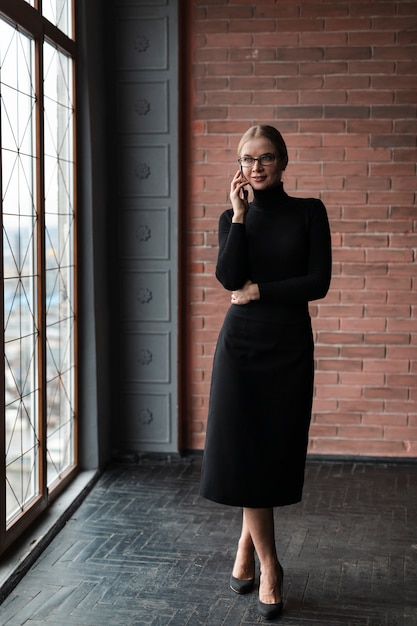 Kobieta przy oknie rozmawia przez telefon
