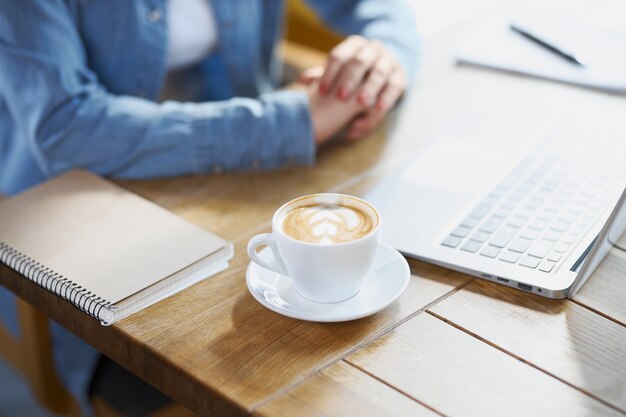 Kobieta przygotowuje się do pracy w kawiarni z laptopem