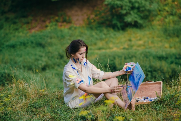 Kobieta retuszowania obrazu siedzi na trawie