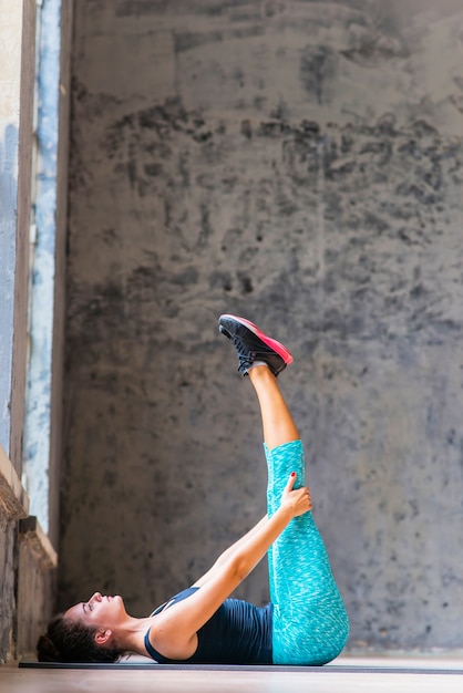 Bezpłatne zdjęcie kobieta robi nóg rozciągania ćwiczeniu na joga macie