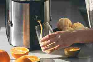Bezpłatne zdjęcie kobieta robi sok pomarańczowy w domu w kuchni za pomocą odciskarki elektrycznej