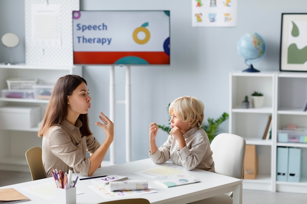 Bezpłatne zdjęcie kobieta robi terapię mowy z małym blond chłopcem