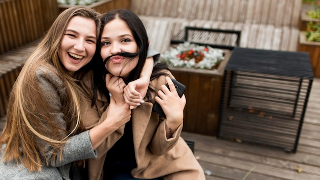 Bezpłatne zdjęcie kobieta robi wąsy z włosami obok swojej przyjaciółki