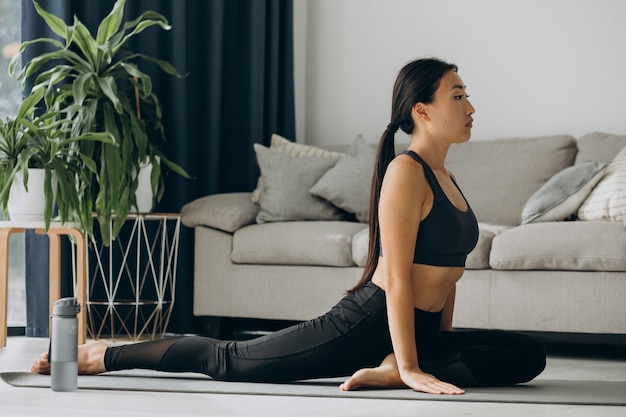 Kobieta rozciągająca się na macie do jogi w domu